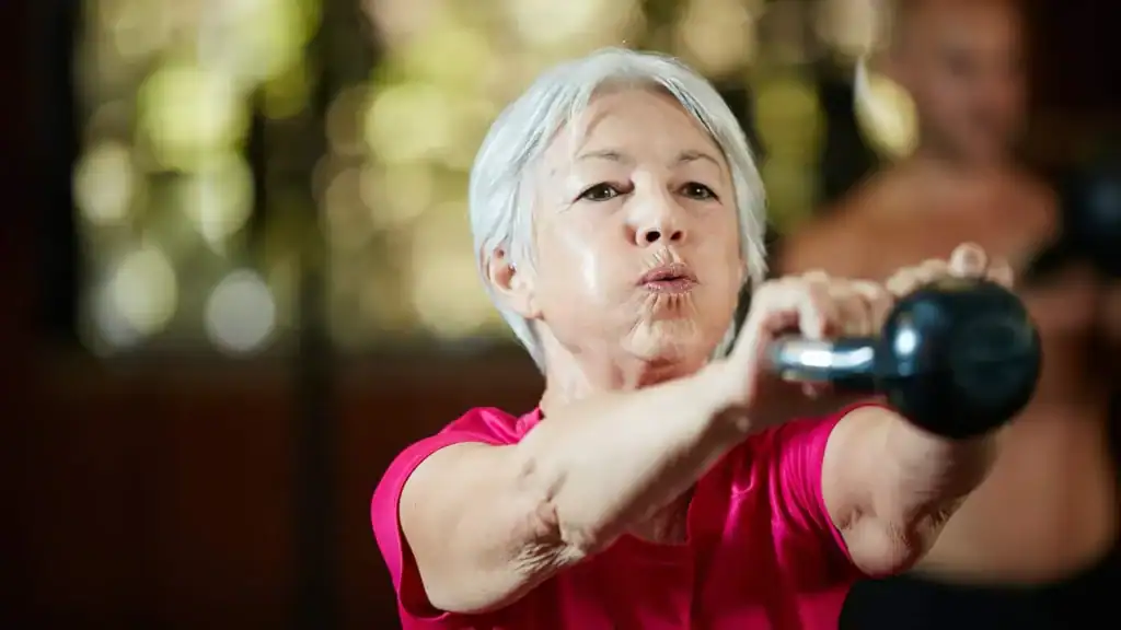 Older woman doing weight training Calne to help her strength and longevity 