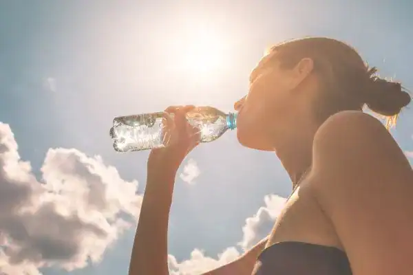 Hydration: The Secret Ingredient for a Toned Stomach and Enhanced Fitness 3 Image of woman drinking water to hydrate Calne after run.