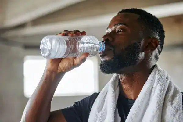 Image of man drinking water to improve hydration Calne after work out.